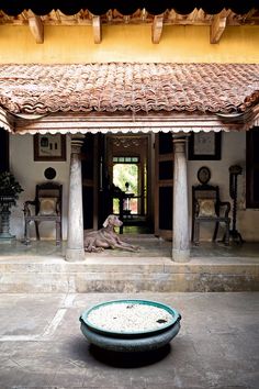 a dog laying on the ground in front of a building with columns and pillars,