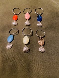 six pairs of rings with seashells on them sitting on a cloth covered surface