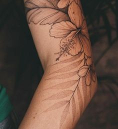 a woman's arm with a flower and leaves tattoo design on the left arm