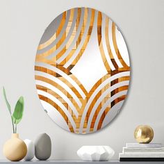 a round mirror sitting on top of a table next to a vase and two white rocks