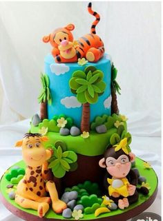 a birthday cake decorated with fondant animals and jungle scenes on it's sides