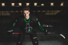 a young man holding a hockey stick on top of an ice covered rink at night