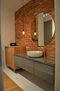 a bathroom with a sink, mirror and brick wall in it's back room