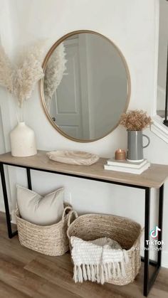 a table with a mirror, basket and vase on it in front of a staircase