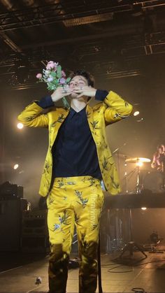 a man standing on top of a stage holding a flower in front of his face