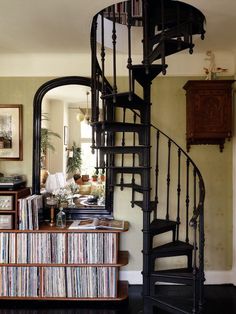 there is a spiral staircase in the living room with records on the floor and an entertainment center