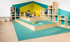 two children are sitting on stairs in a playroom with bookshelves and shelves