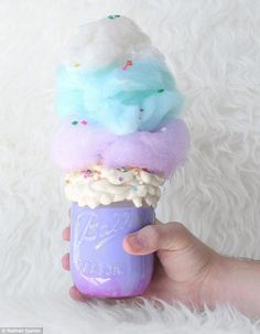 a hand is holding an ice cream cone with sprinkles and rainbow colors