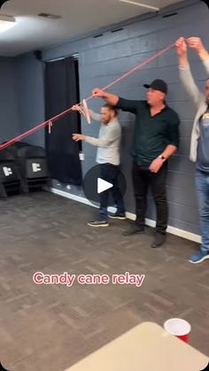 three men are playing tug ropes in an empty room with the caption candy cane relay