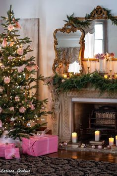 a decorated christmas tree sitting in front of a fire place with candles and presents on the mantle