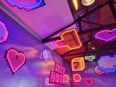 colorful neon signs hang from the ceiling in a room with purple walls and white ceilings