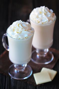 two glasses filled with whipped cream on top of a table