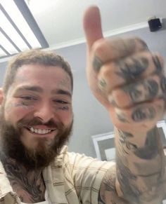 a man with tattoos giving the thumbs up