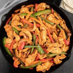 a skillet filled with chicken, peppers and onions