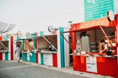 two people are standing at the outside of a colorful food stand that has red, white and blue stripes on it