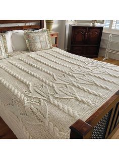 a bed with a white crocheted blanket on top of it next to a window