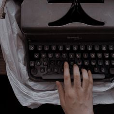 someone typing on an old fashioned typewriter with their hand over the top of it