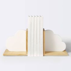 three books are stacked on top of each other in front of a white cloud shaped bookend