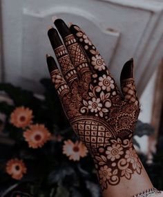 a woman's hand with hennap on it and flowers in the background