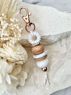 a keychain with flowers on it sitting next to a white flower and some other items