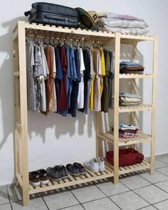 a wooden rack with clothes and shoes hanging on the wall next to a tiled floor