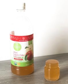 a bottle of apple cider vinegar next to a jar of honey on a table