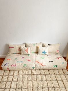 a bed sitting on top of a wooden floor next to a white wall