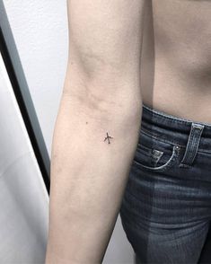 a person with a small cross tattoo on their arm