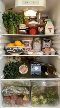 an open refrigerator filled with lots of different types of vegetables and food in plastic containers