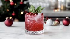 a red drink sitting on top of a white counter next to christmas ornaments and a tree