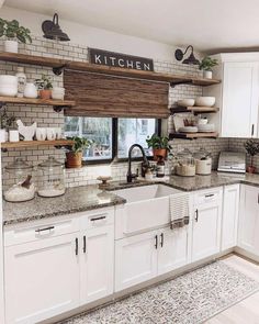 a kitchen filled with lots of white cupboards and counter top space next to a window