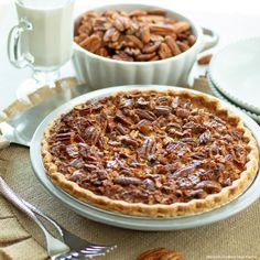 a pecan pie sitting on top of a table next to a cup of coffee