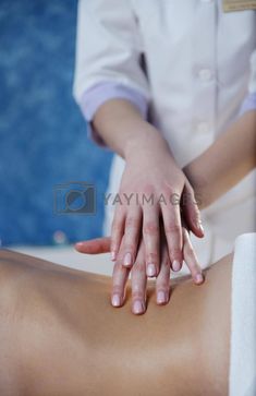 a woman getting a back massage at the spa or beauty salon with her hands on top