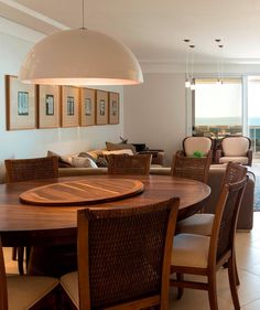 a dining room table with chairs and an oval wooden table in front of a large window