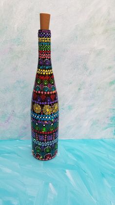 a colorful bottle with a cork top on a blue surface in front of a white wall