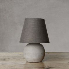 a table lamp sitting on top of a wooden table next to a white ball with a gray shade