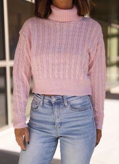 a woman in pink sweater and jeans posing for the camera with her hand on her hip