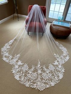 a wedding veil is laying on the floor in front of a red chair and window