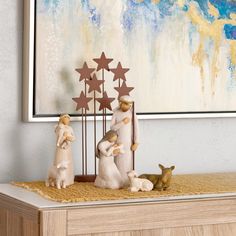 three small figurines are sitting on a table next to a painting and two deer