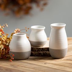 three white vases sitting on top of a wooden table