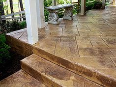 some steps leading up to a porch with a bench on one side and bushes in the other