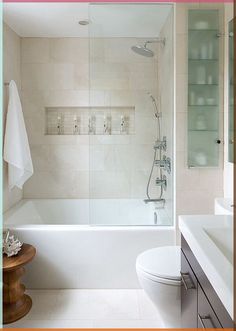 a bathroom with a toilet, sink and bathtub next to a shower door that has glass shelves on the wall