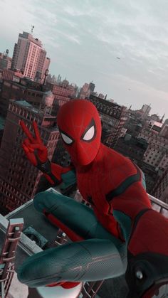 the spider - man is sitting on top of a building