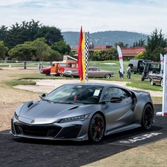 a silver sports car parked on top of a parking lot next to a red flag