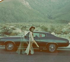 two women walking past an old car in the desert