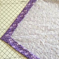 a piece of fabric is laying on top of a cutting board with purple and white polka dots