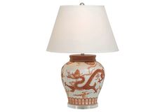 a lamp that has a dragon on it and a white shade in front of it