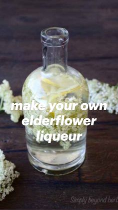 a glass bottle filled with water and lemon slices on top of a wooden table next to flowers