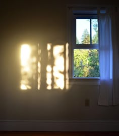 the sunlight is shining through two windows in an empty room