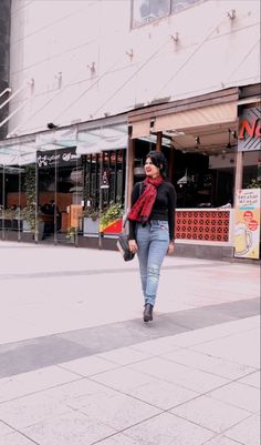 a woman walking down the street in front of a building